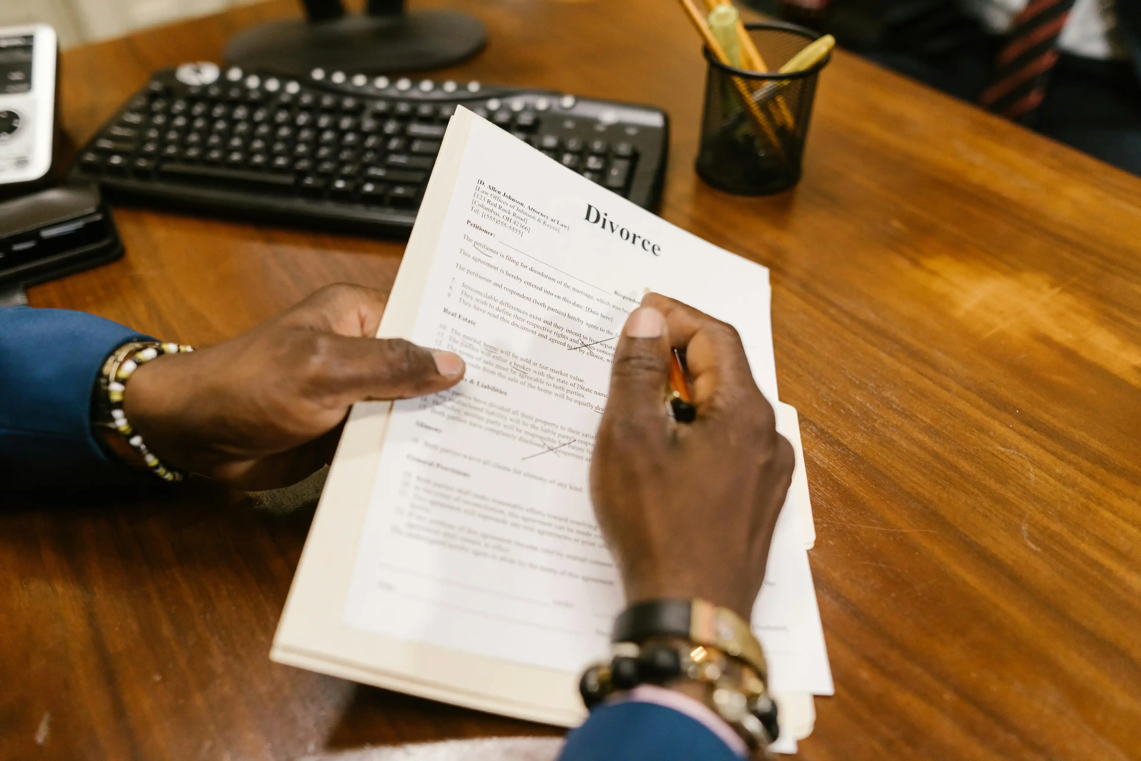 An attorney holds Divorce paperwork, crossing out unneeded paragraphs for the clients.