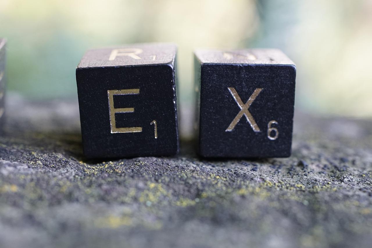 Two Scrabble pieces next to each other spelling out the word: Ex